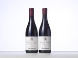 two bottles of red wine sitting on top of a white table