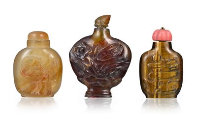 trois flacons à tabac en verre posés les uns à côté des autres sur une surface blanche