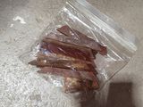 a bag of bacon sitting on the floor next to a person ' s hand