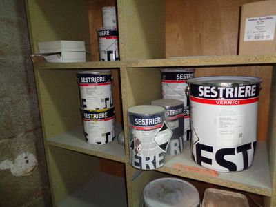 plusieurs seaux de peinture posés sur une étagère dans une pièce