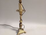 an antique brass table lamp with a black cord on a white background