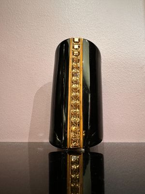 un vase noir orné d'une bordure dorée posé sur une table noire