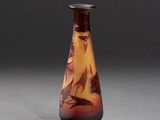 un vase orange et marron orné d'oiseaux, posé sur une surface grise
