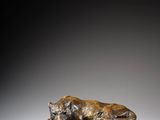 a bronze statue of a dog laying on a rock