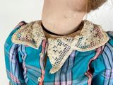 a doll that is wearing a blue shirt with a lace collar