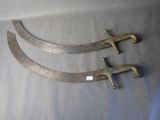 pair of antique brass swords on a table with a white background