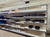 many empty shelves in a store with plastic containers on them