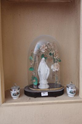 un dôme en verre renfermant une statue, posé sur une étagère