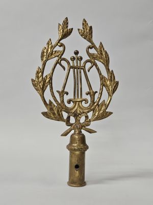 une image représentant une plaque en laiton ornée d'une harpe et de branches de laurier