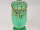 a green vase with gold decoration on it on a white surface