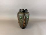 a green vase with a black lid sitting on a table