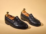 a pair of black leather shoes on a yellow background