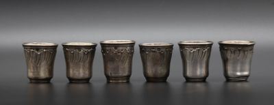 six verres à shot en argent alignés sur une table