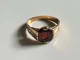 a close up of a gold ring with a red stone in it