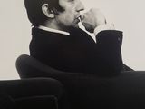 black and white photograph of a man sitting in a chair with his hand on his chin