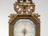 une horloge dorée avec un cadran bleu, surmontée d'un oiseau