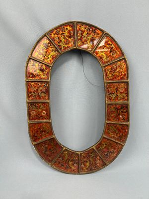 une lettre « o » décorée en orange et or sur fond blanc