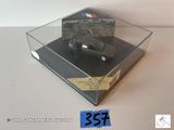 une voiture noire dans une vitrine transparente posée sur une table