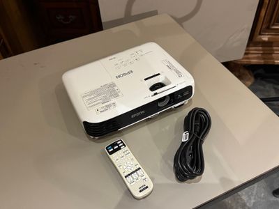 a white projector sitting on a table next to a remote control
