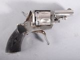 un revolver argenté posé sur une surface blanche, avec une crosse noire