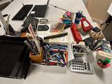 une table blanche sur laquelle se trouvent un ordinateur portable et de nombreuses fournitures de bureau