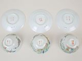 four chinese porcelain bowls and saucers are lined up on a white surface