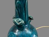 a blue vase with a bird on it on a table