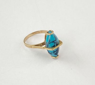 gros plan d'une bague en or avec une pierre turquoise