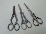 three pairs of silver scissors sitting next to each other on a table