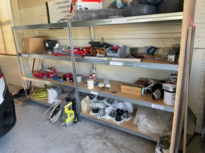 une voiture garée dans un garage, à côté d'une étagère remplie d'outils