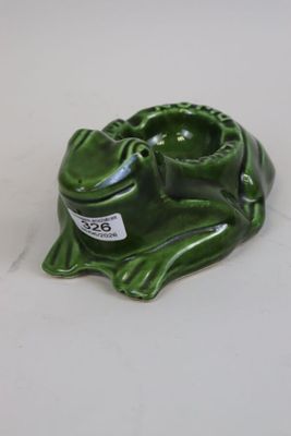 a green frog that is sitting on a white table