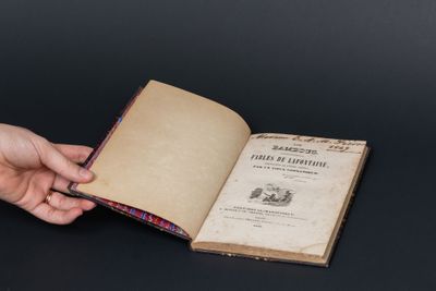 une personne tenant un livre ouvert sur une table, sur fond noir