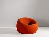 une chaise orange posée sur un sol blanc, à côté d'un mur blanc