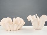 two white vases sitting on a table with a gray background