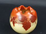 an orange and white vase with red leaves on it