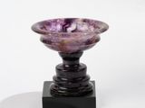 a purple marble bowl sitting on a black stand
