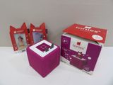 une petite boîte violette posée sur une table, à côté d'une boîte sur laquelle est représenté un chat