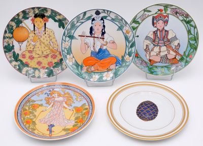 four decorative plates with asian designs on them sitting on a white surface