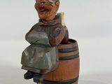 a small wooden figurine of a man sitting on a barrel