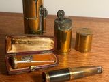 une petite boîte en laiton contenant un stylo et d'autres objets, posée sur une table en bois