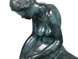 statue of a man sitting on a rock with his hands on his knees