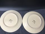 two white plates with black writing on them sitting on a blue cloth