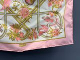 a pink and gold scarf hanging on a blue wall