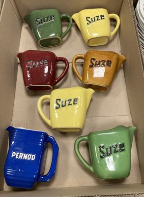 six tasses de couleurs différentes dans une boîte, sur lesquelles figurent des prénoms