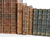 several old books are lined up in a row on a white surface