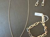 silver necklace and earring set on a black leather surface