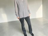 woman standing in an empty room wearing a grey shirt and black jeans