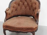 une vieille chaise dont l'assise et le dossier sont recouverts de tissu marron