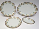 three plates and two bowls with flowers on them on a white surface