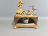 a gold clock with a statue of a woman on a carriage